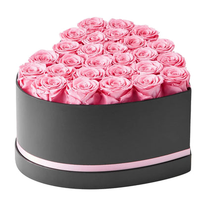 Heart-shaped box filled with pink roses on a white background
